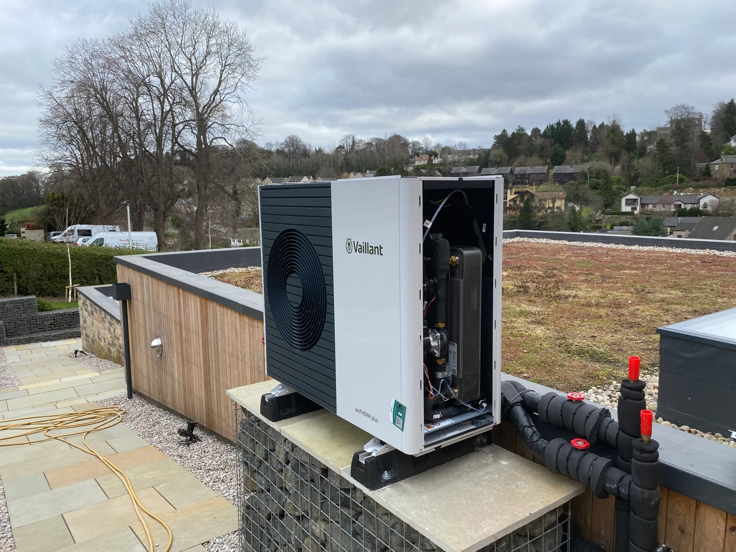 A Vaillant aroTHERM plus air source heat pump outside a house, its casing open