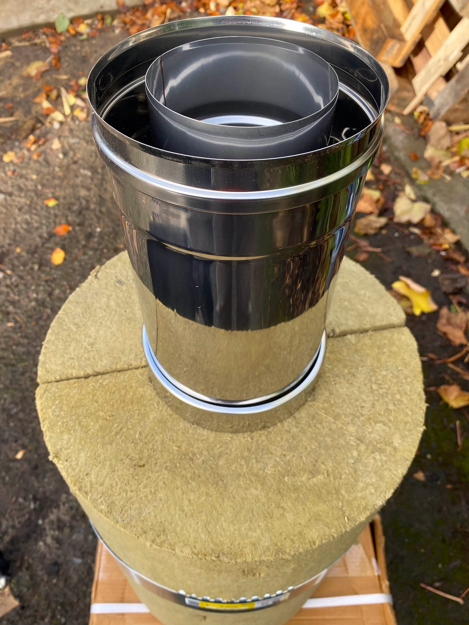 A section of triple-wall chimney: three concentric stainless skins standing on the insulated sleeve