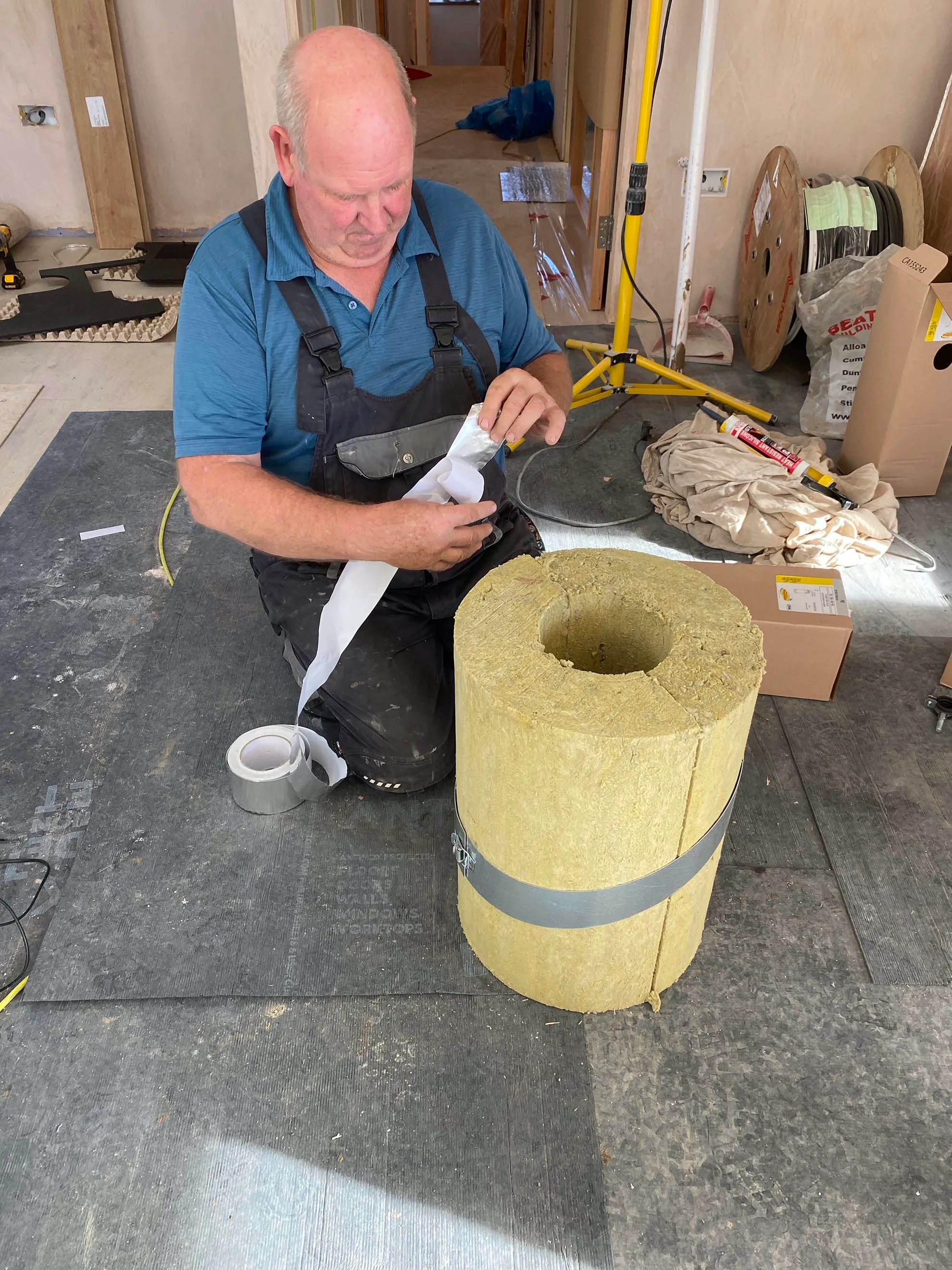 Taping the high-density mineral wool sleeve that closes the insulation gap round the chimney