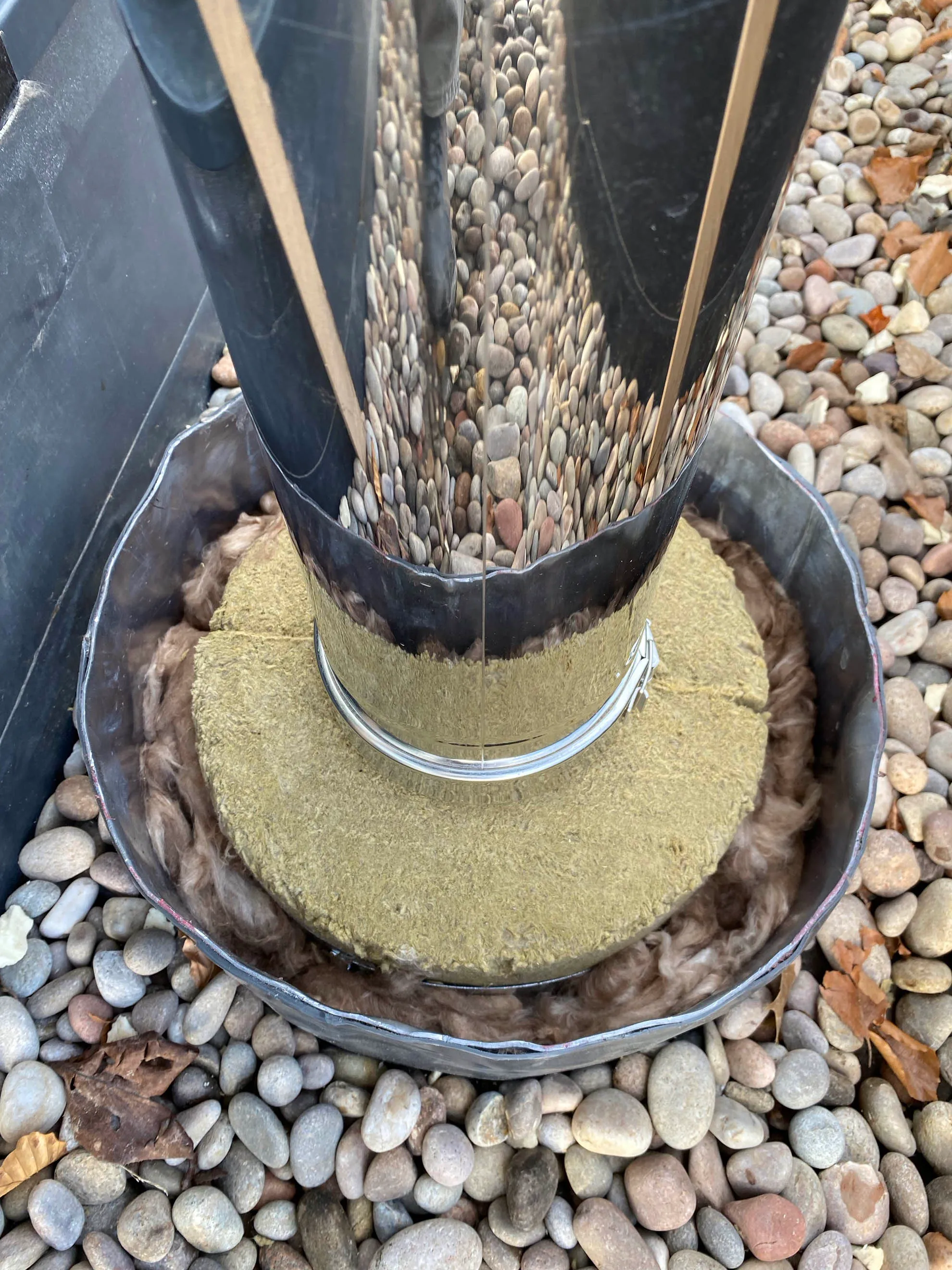 The insulated sleeve packed round the flue where it passes through the roof, sealed in a metal tray