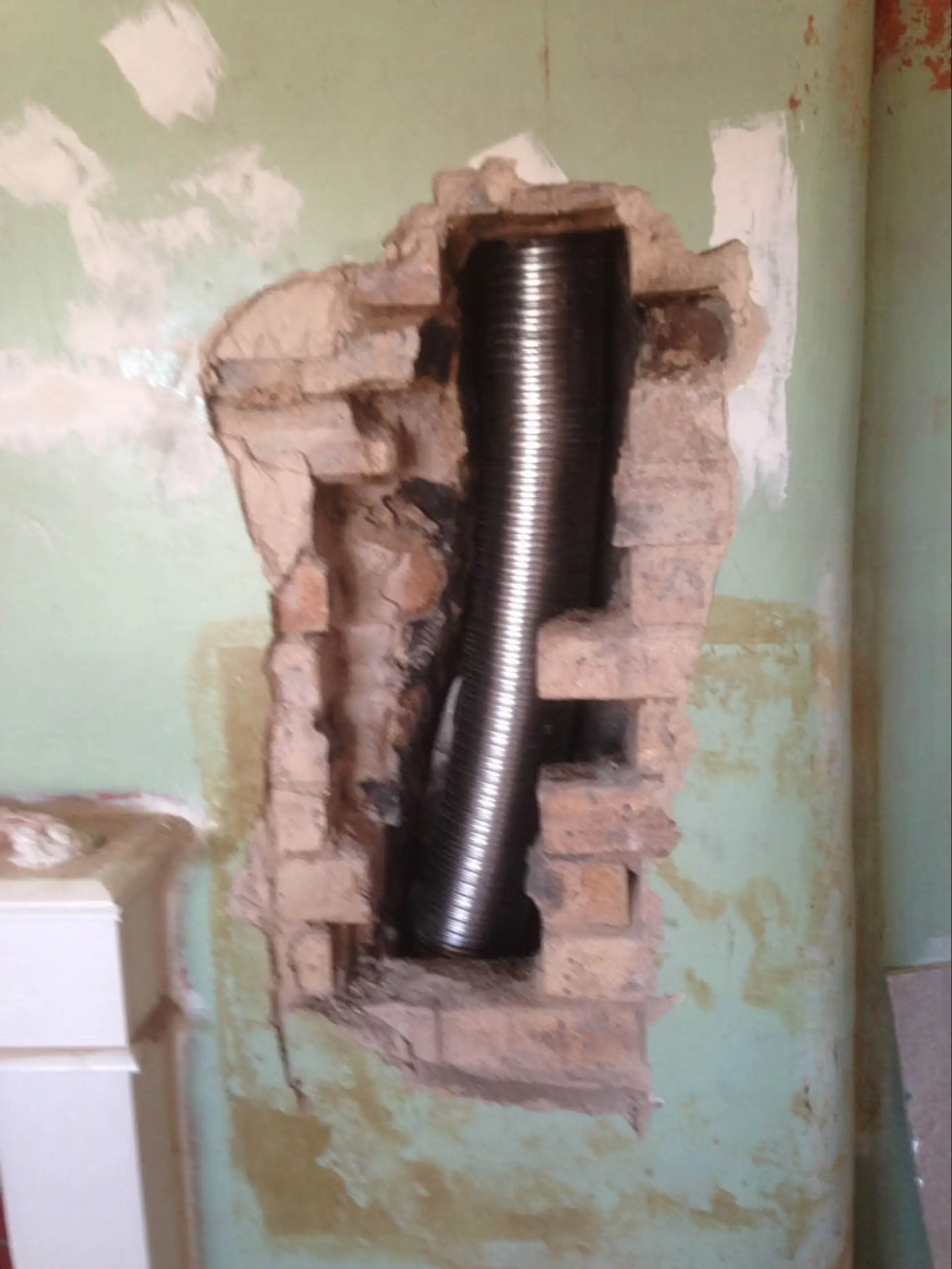 The flexible chimney liner being fed into the opened chimney breast