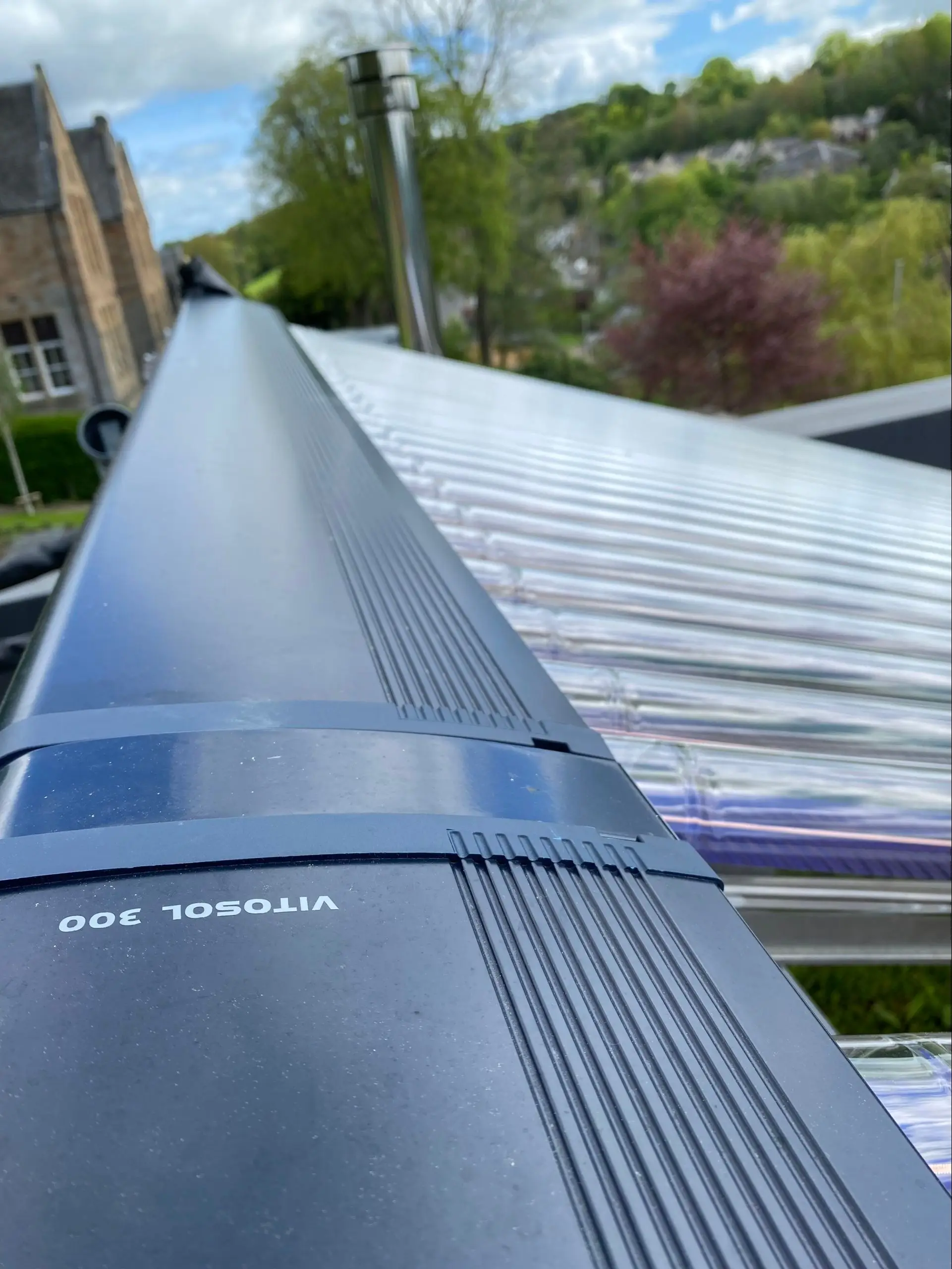 Flat‑plate solar collectors on a ground‑mounted frame in the garden of a stone house
