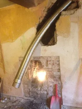 A flexible liner fed down through the opened chimney breast into the fireplace