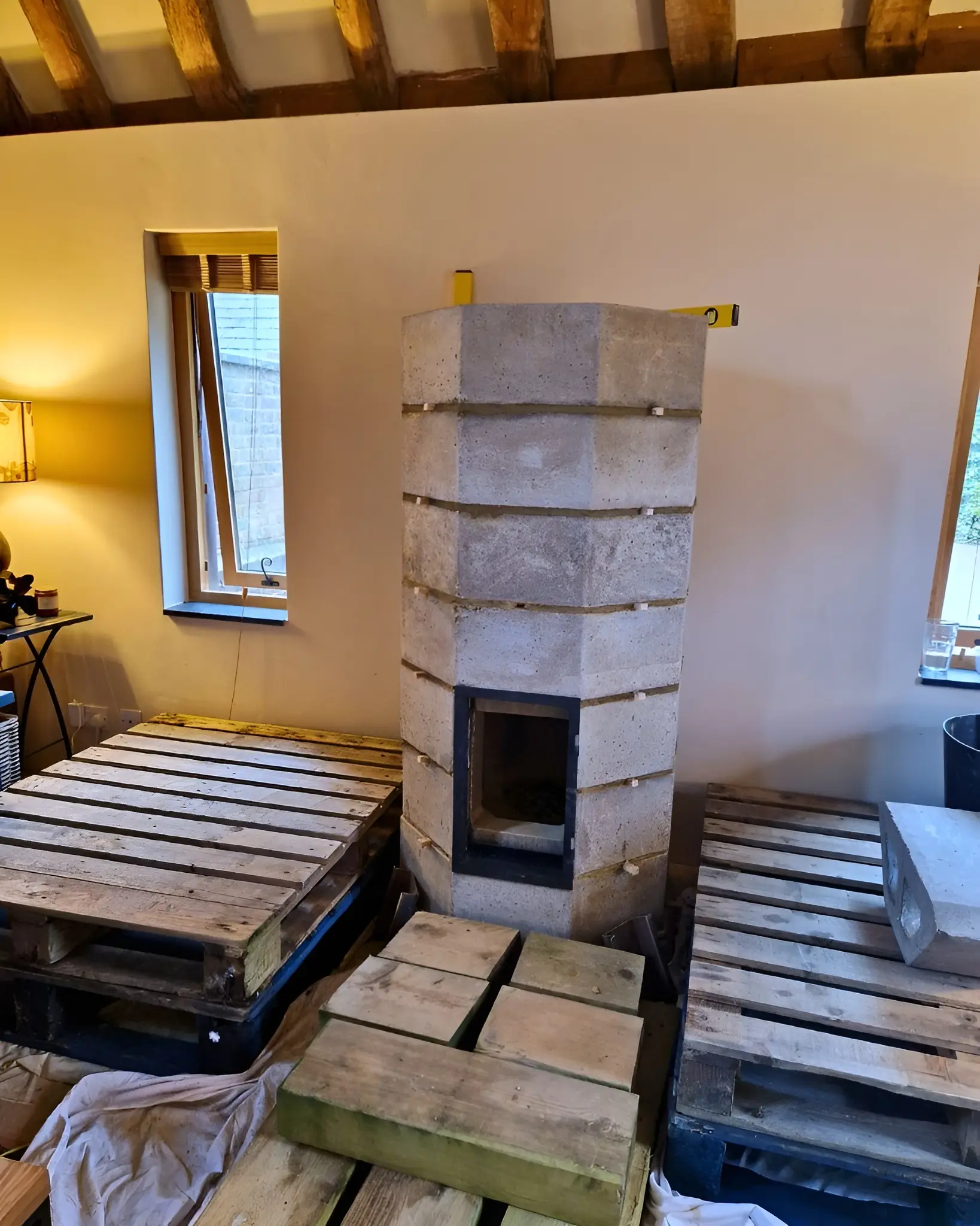 An Osier masonry heater part-built in raw blocks, a spirit level resting on top